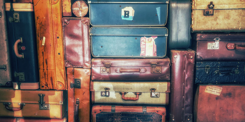 A tightly packed collection of vintage suitcases in many colours.