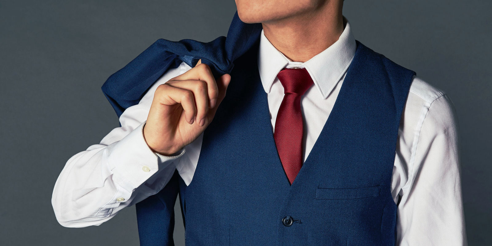 the midsection of a smartly dressed man showing his deep brown suit and waistcoat.