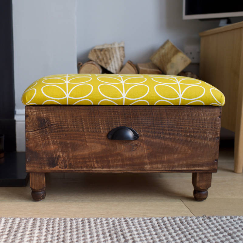 An ottoman with a dark finish and yellow leaf motif pattern.